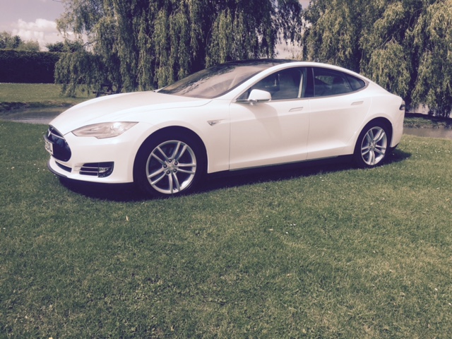 Tesla side view with wheel alloys on display in field