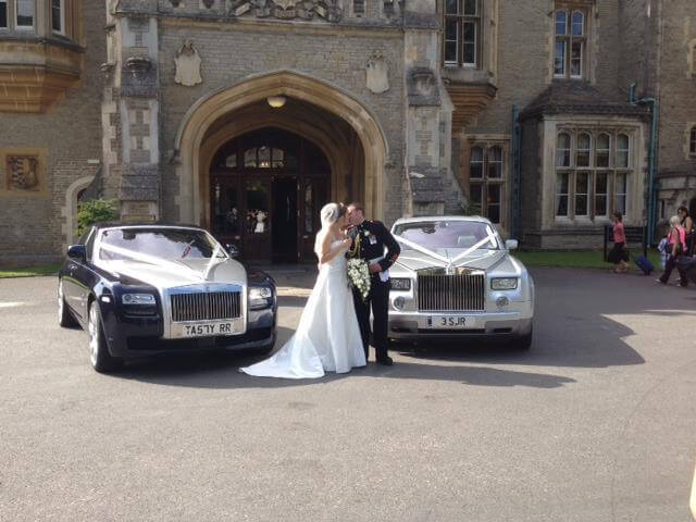couple kissing in front of church with two rolls royce vintage and classic cars for wedding