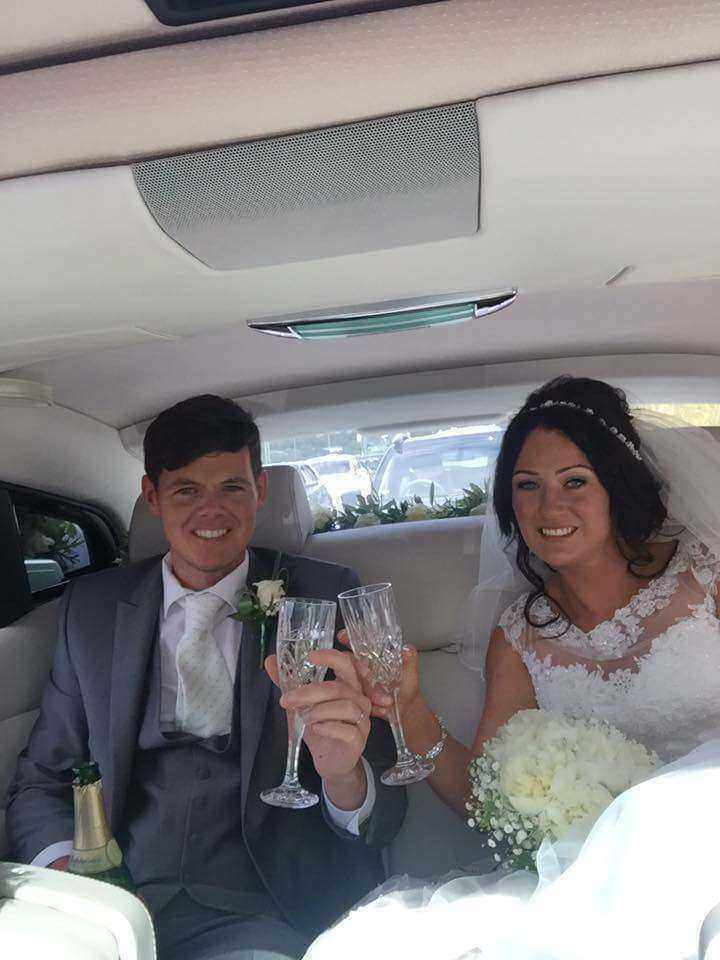 bride and groom in car having champagne