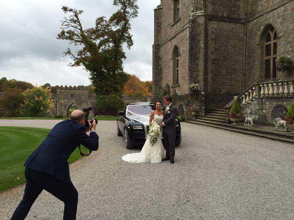 couple being photographed next to the rolls royce wedding car