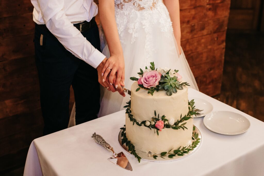Bridge and groom cutting a two tiered wedding cake with roses 