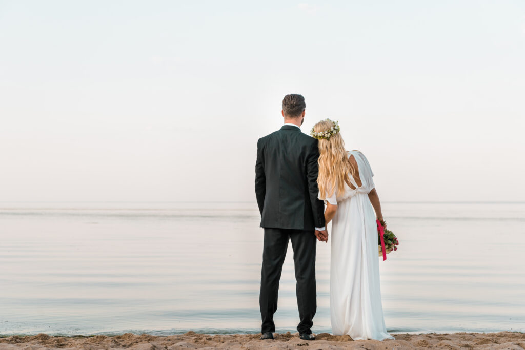 married couple standing on a beach 