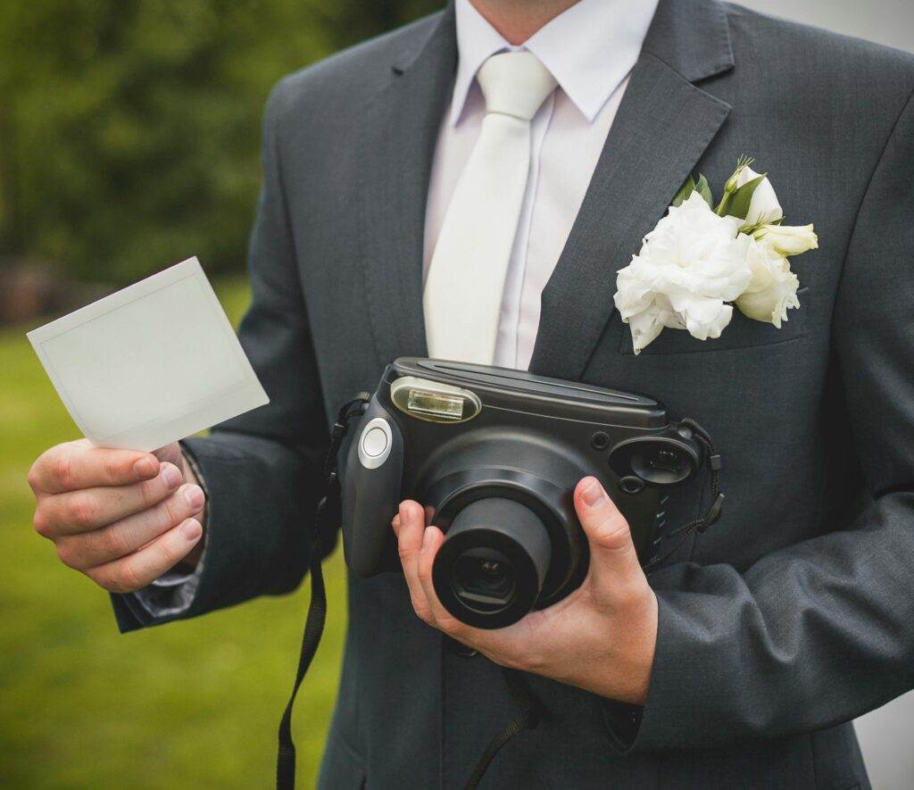 part-of-groom-with-retro-camera-and-empty-card
